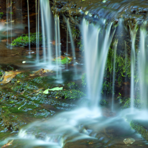 A small waterfall cascades over moss-covered rocks.