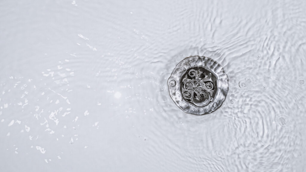 Water swirling around a circular metal drain in a sink.