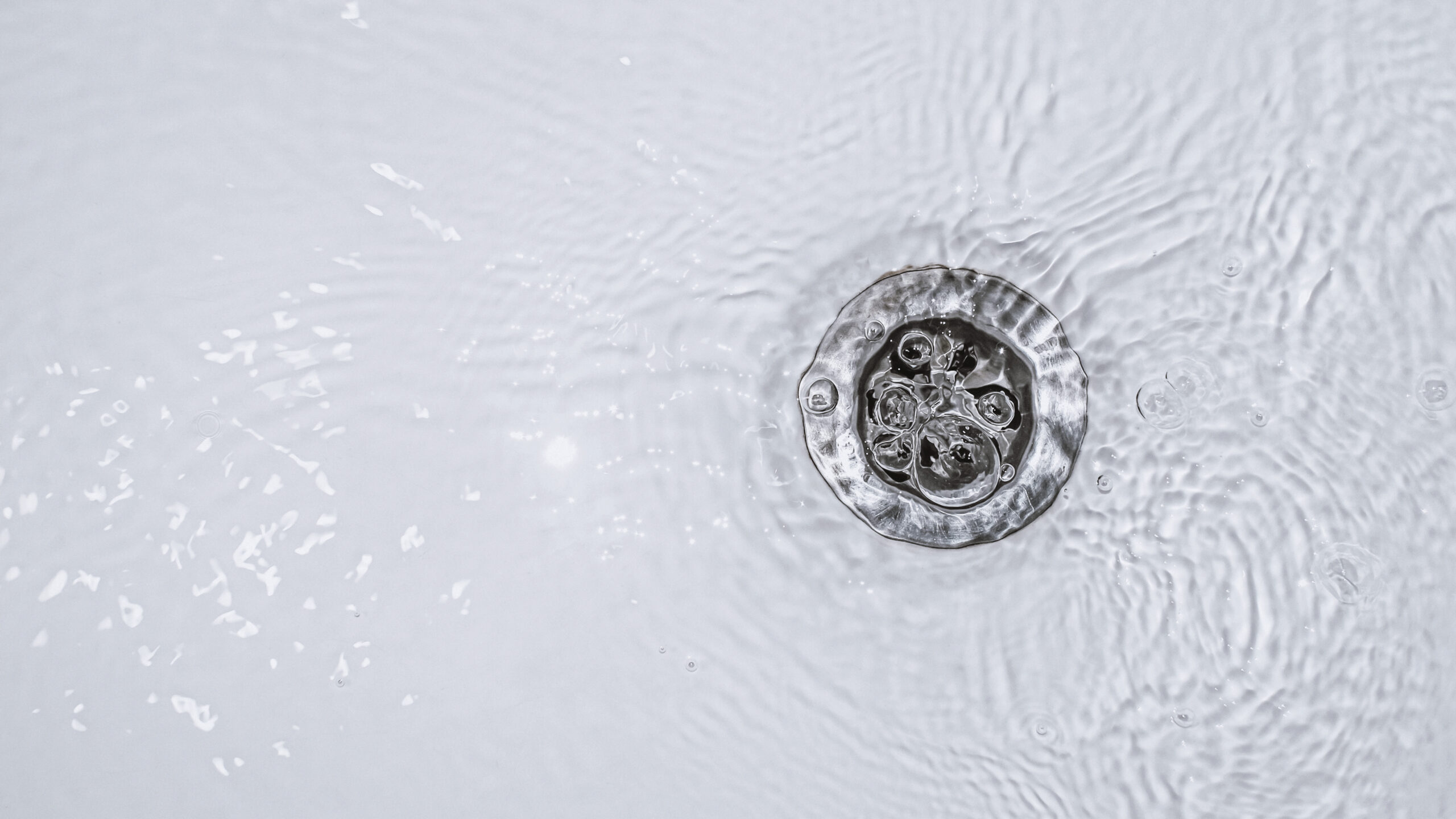 Water swirling around a circular metal drain in a sink.